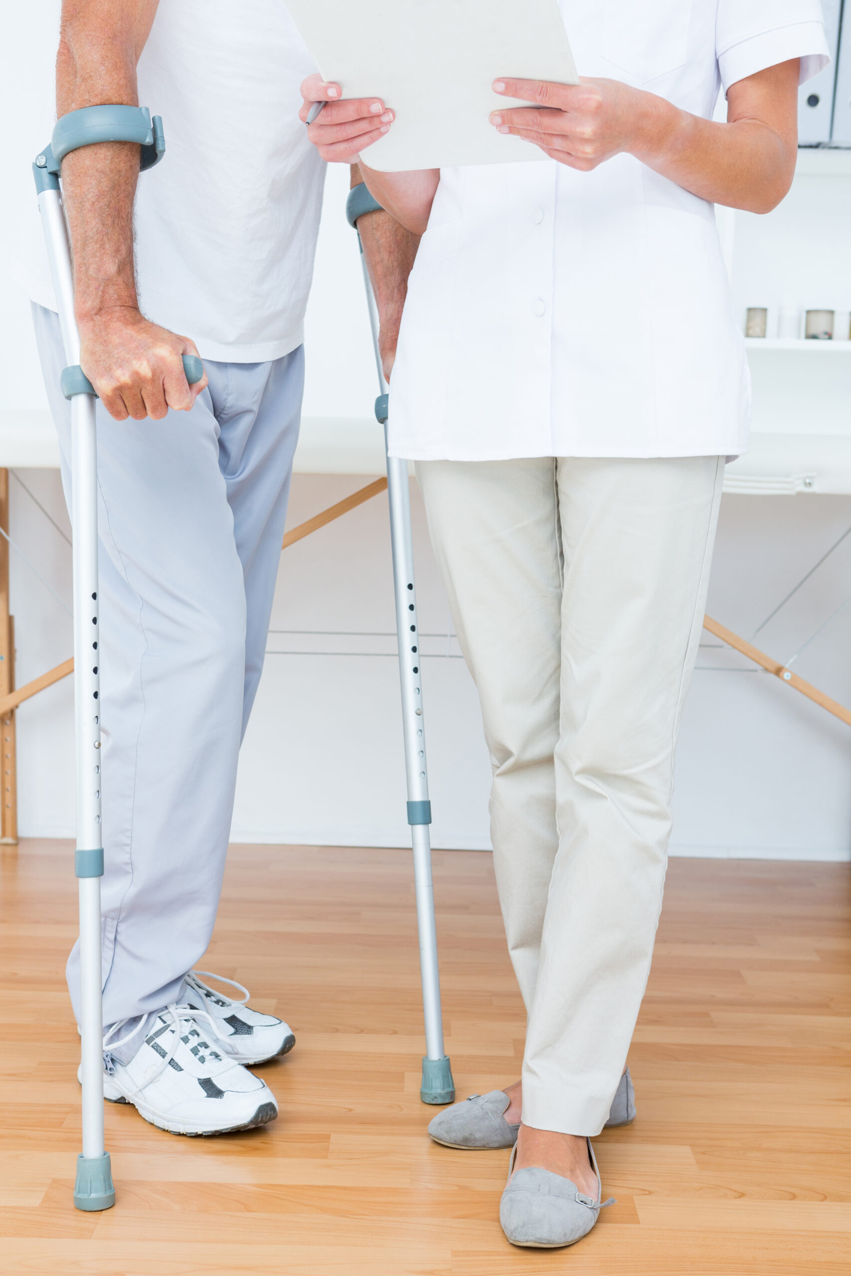 Doctor showing clipboard to her patient with crutch in medical office